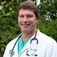 smiling male veterinarian wearing white lab coat and stethoscope